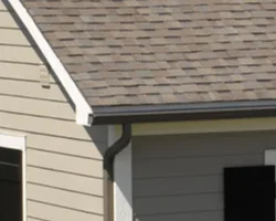 Seamless gutter and downspout along a shingle roofline
