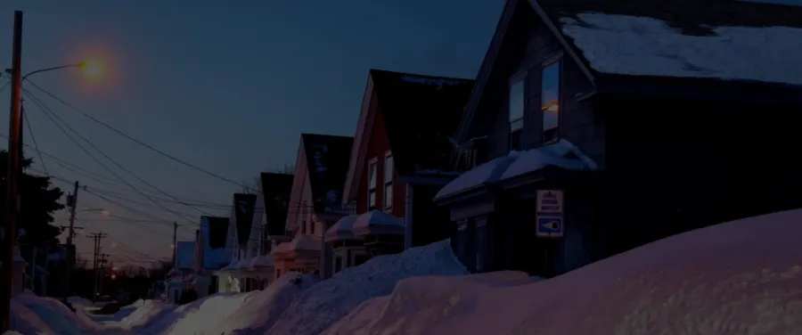 Snow-covered New England neighborhood at dusk